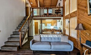 A cozy cabin interior with a staircase leading to a loft bedroom, a dining area, and a kitchen. - Welcome to Your Ultimate Sierra Escape in Blue Lake Springs! (Arnold)