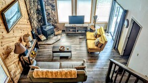 Ein gemütliches Wohnzimmer mit Steinwand, Kamin, einer Couch, einem Couchtisch und einem Fernseher.
