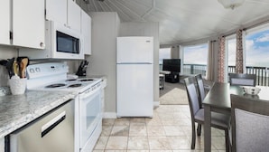 A compact kitchen with a stove, microwave, and refrigerator, leading to a dining area with a table and chairs.
