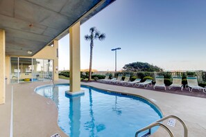 An outdoor swimming pool with lounge chairs, palm trees, and a building with glass doors. - Recently Updated, Wonderful Oceanfront Views + Free Attraction Tickets! (North Myrtle Beach)