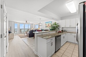 A modern kitchen with white cabinets, a central island, and a view to the outside.