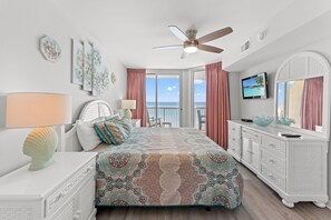 A bedroom with a bed, a dresser, a television, and a ceiling fan.