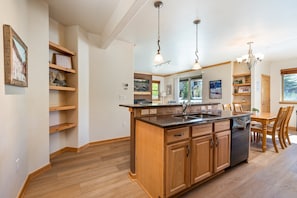 Une cuisine moderne avec des meubles en bois, un îlot central et des luminaires suspendus.