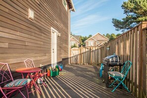 Eine Holzterrasse mit Gartenmöbeln, einem Grill und einem Holzzaun.