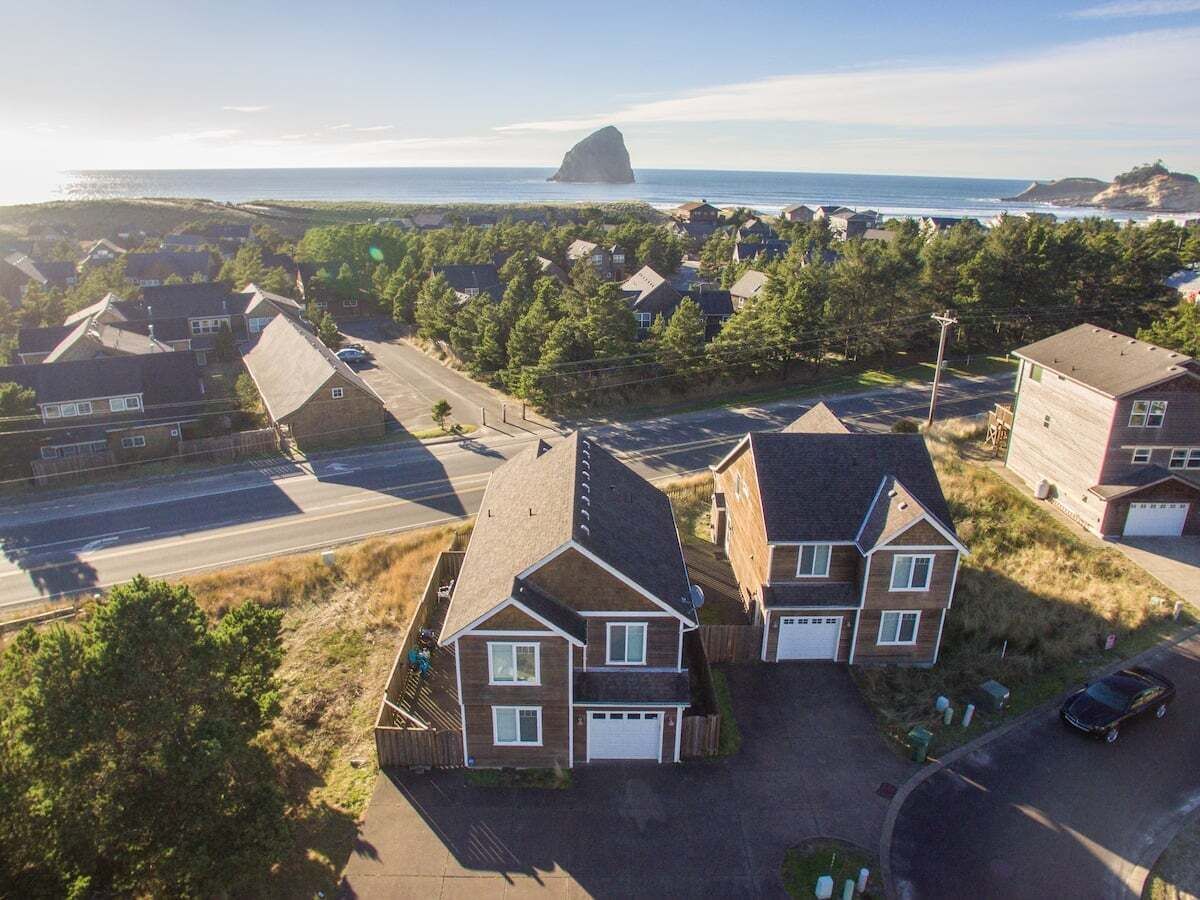A residential area with houses, a road, and a large rock formation by the sea.