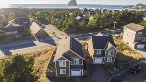 Zona residencial con casas, una carretera y una gran formación rocosa junto al mar.