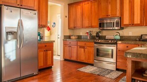 Una cocina con armarios de madera, electrodomésticos de acero inoxidable y encimera de granito.