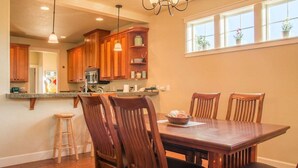 Una cocina con armarios de madera, una mesa de comedor con sillas y una barra con taburetes.