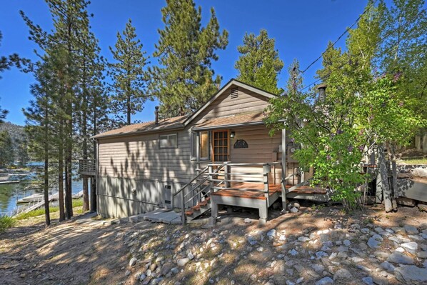 A cabin with a wooden deck, a small porch, and a view of a lake.