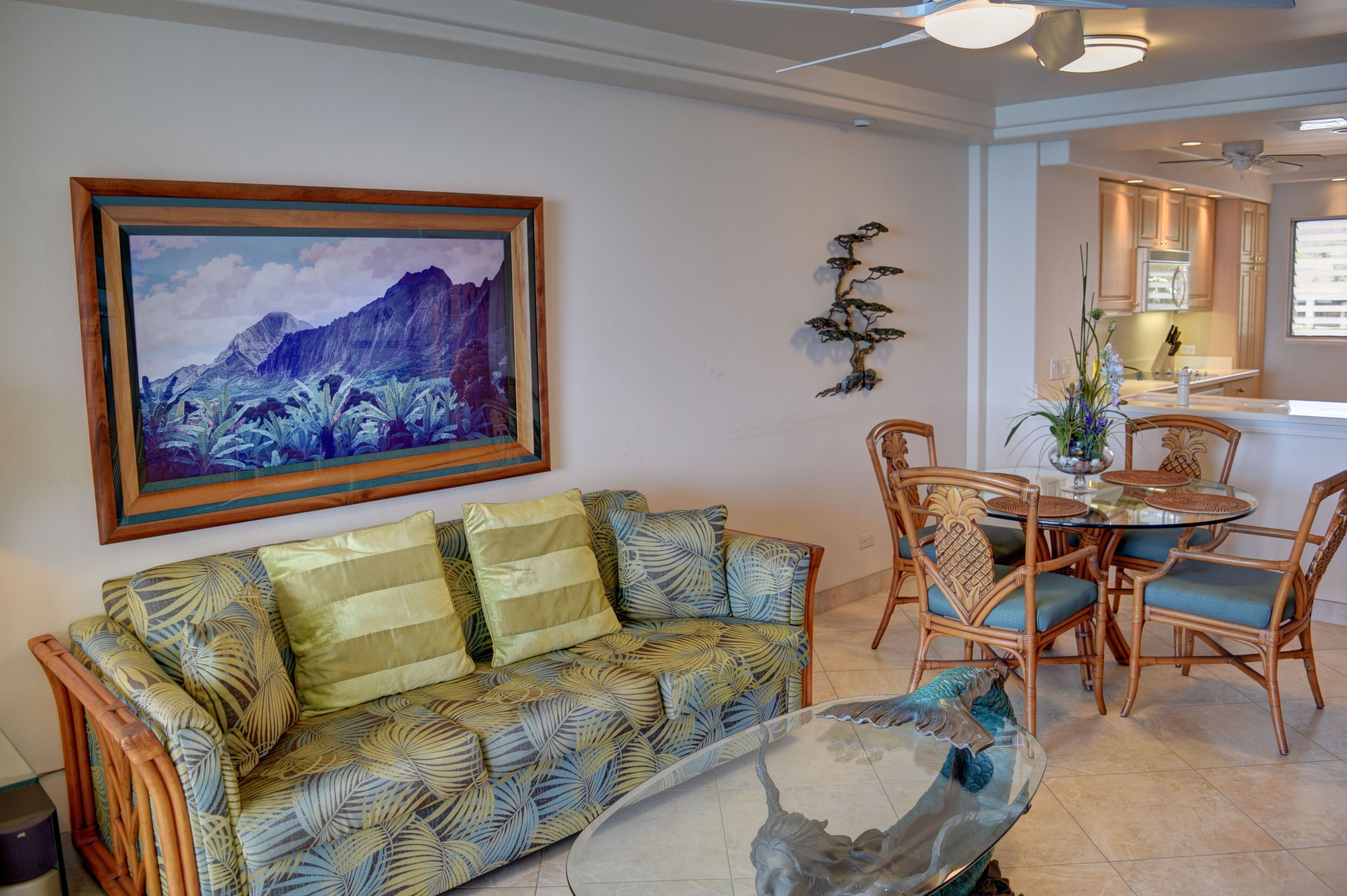 A living room with a sofa, dining table, chairs, and a painting on the wall.