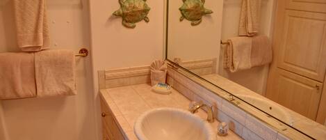 A bathroom with a sink, mirror, towel rack, and a decorative turtle wall piece.