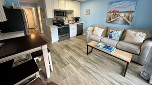 A compact living space with a kitchenette, a dining area, and a seating area with a sofa and coffee table.