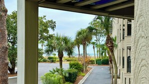 A covered outdoor area with a view of a road, palm trees, and a building in the background.