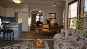 Un salon comprenant un canapé, une table basse avec des bougies et un coin repas avec des chaises et une table.