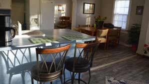 Une cuisine dotée d’un îlot central, de tabourets de bar, d ’une table à manger avec des chaises et d’un réfrigérateur.