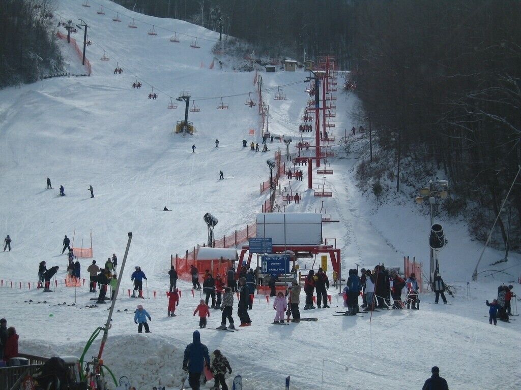 A ski slope with people skiing and a ski lift in operation.