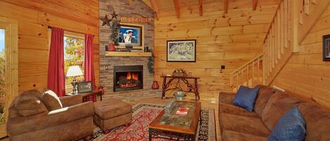 L’intérieur d’un chalet confortable, avec une cheminée, des murs en bois et un tapis rouge à motifs.