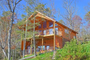 A log cabin with a two-story balcony and a stone foundation. - Cozy, Affordable Mountain Retreat (Gatlinburg)