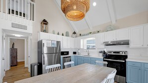 A kitchen with white cabinets, a wooden table, and a chandelier. - Gulf Front | Pet Friendly | Shared Heated Pool (Gulf Shores)