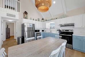 Una cocina con armarios blancos, una mesa de madera y una araña.