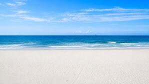 A beach with clear blue water and a sandy shore. - Gulf Front | Pet Friendly | Shared Heated Pool (Gulf Shores)