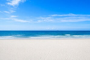 A beach with clear blue water and a sandy shore.