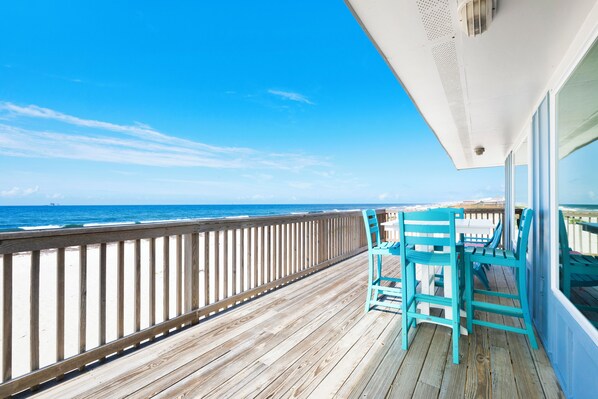 A wooden deck with a railing, overlooking the ocean.