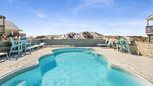 A swimming pool with a wooden deck, surrounded by lounge chairs and a wooden fence. - Gulf Front | Pet Friendly | Shared Heated Pool (Gulf Shores)