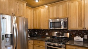 A kitchen with wooden cabinets, stainless steel appliances including a refrigerator, microwave, stove, and oven.