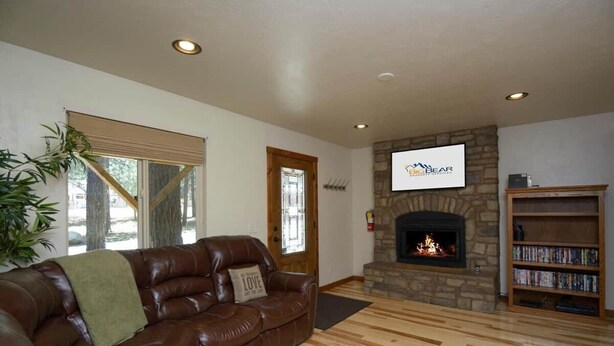 A living room with a leather sofa, a stone fireplace, and a bookshelf.