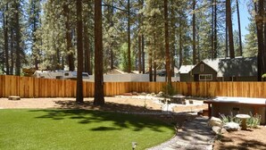 A fenced backyard with a lawn, a wooden deck, and a small shed.