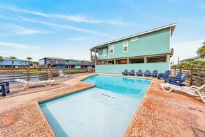 A swimming pool with lounge chairs and a wooden deck.