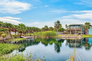 A tranquil lakeside setting with a house featuring a wooden deck and a covered outdoor seating area.