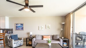 A modern living room with a sofa, armchair, coffee table, and a ceiling fan. - Oceanfront, walk to shops and restaurants (Kihei)