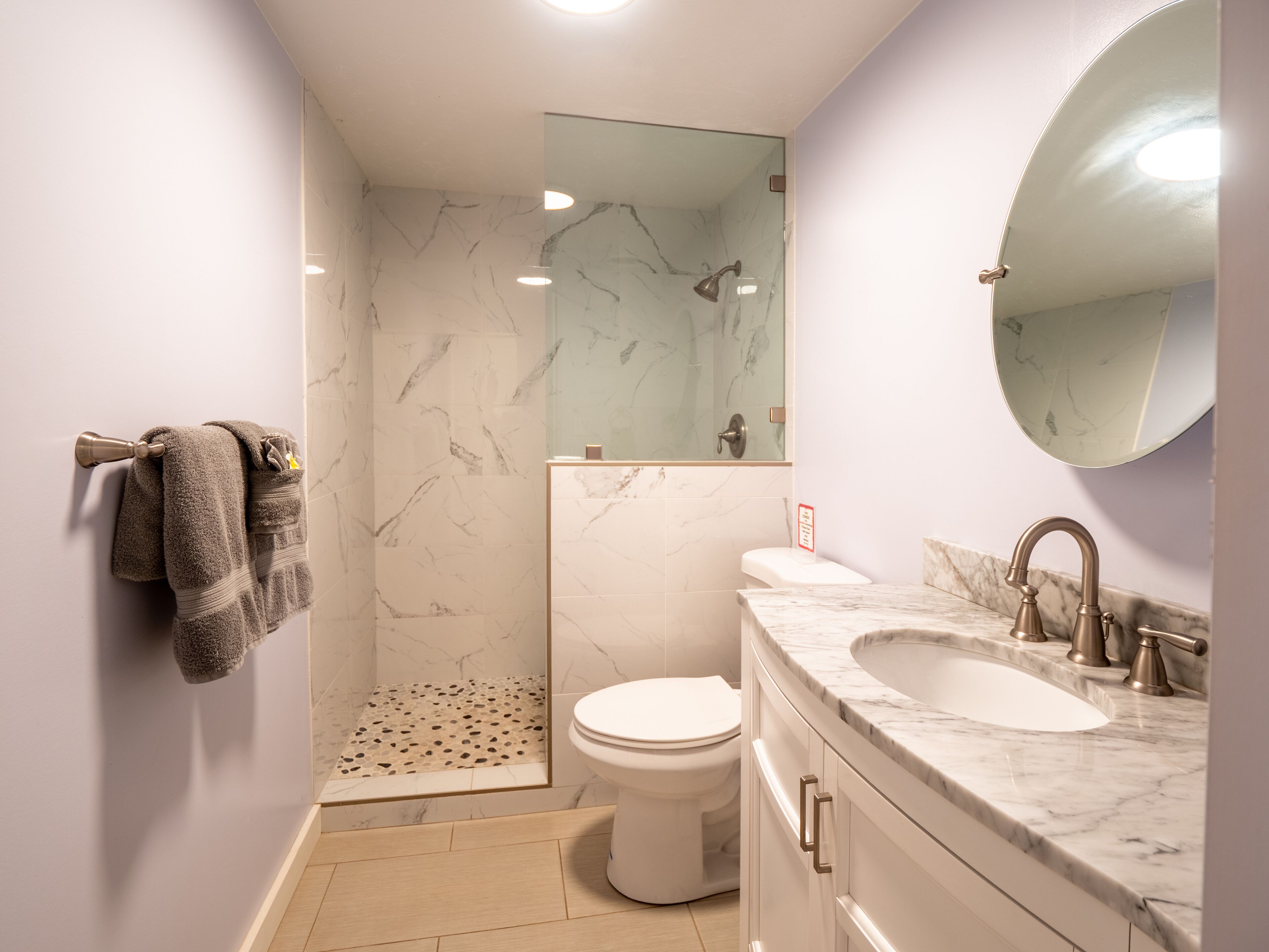 A modern bathroom with a shower, toilet, and sink.