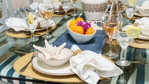 A dining table set with glassware, plates, and a bowl of fruit. - 🌴Welcome to The Islander Unit #203 Your Perfect Destin Beach Escape🌅 (Destin)