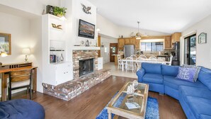 Uma sala de estar ampla com lareira, área de jantar e cozinha.
