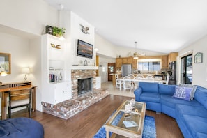 A spacious living room with a fireplace, a dining area, and a kitchen.
