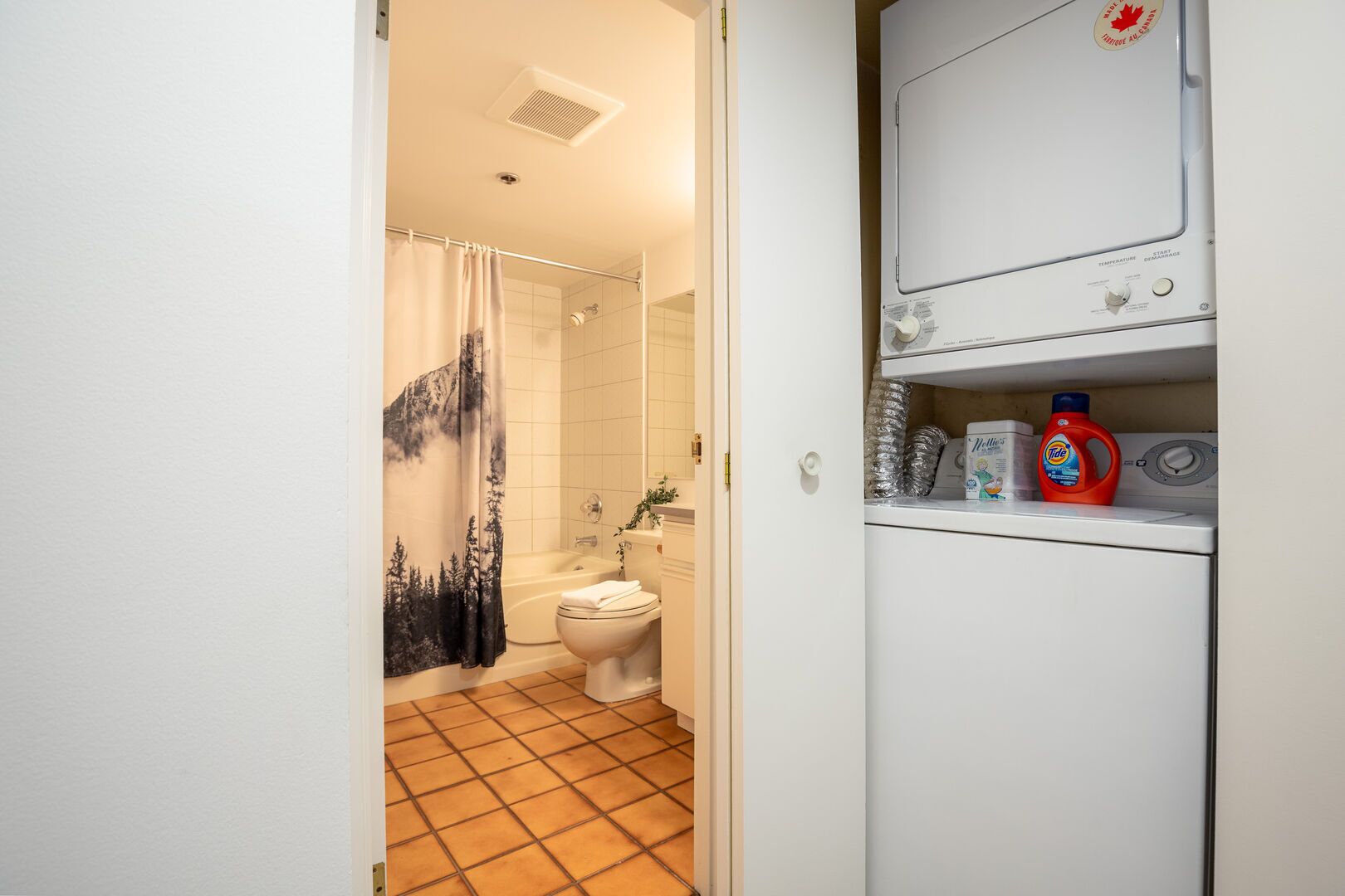Un baño con ducha, inodoro y lavadora.