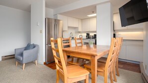 A modern kitchen with white cabinets, a stainless steel refrigerator, and a dining table with wooden chairs. - 1BR | Carleton Lodge | Unbeatable Mountain Base Location | Ski in / out | | Free Parking (Whistler)