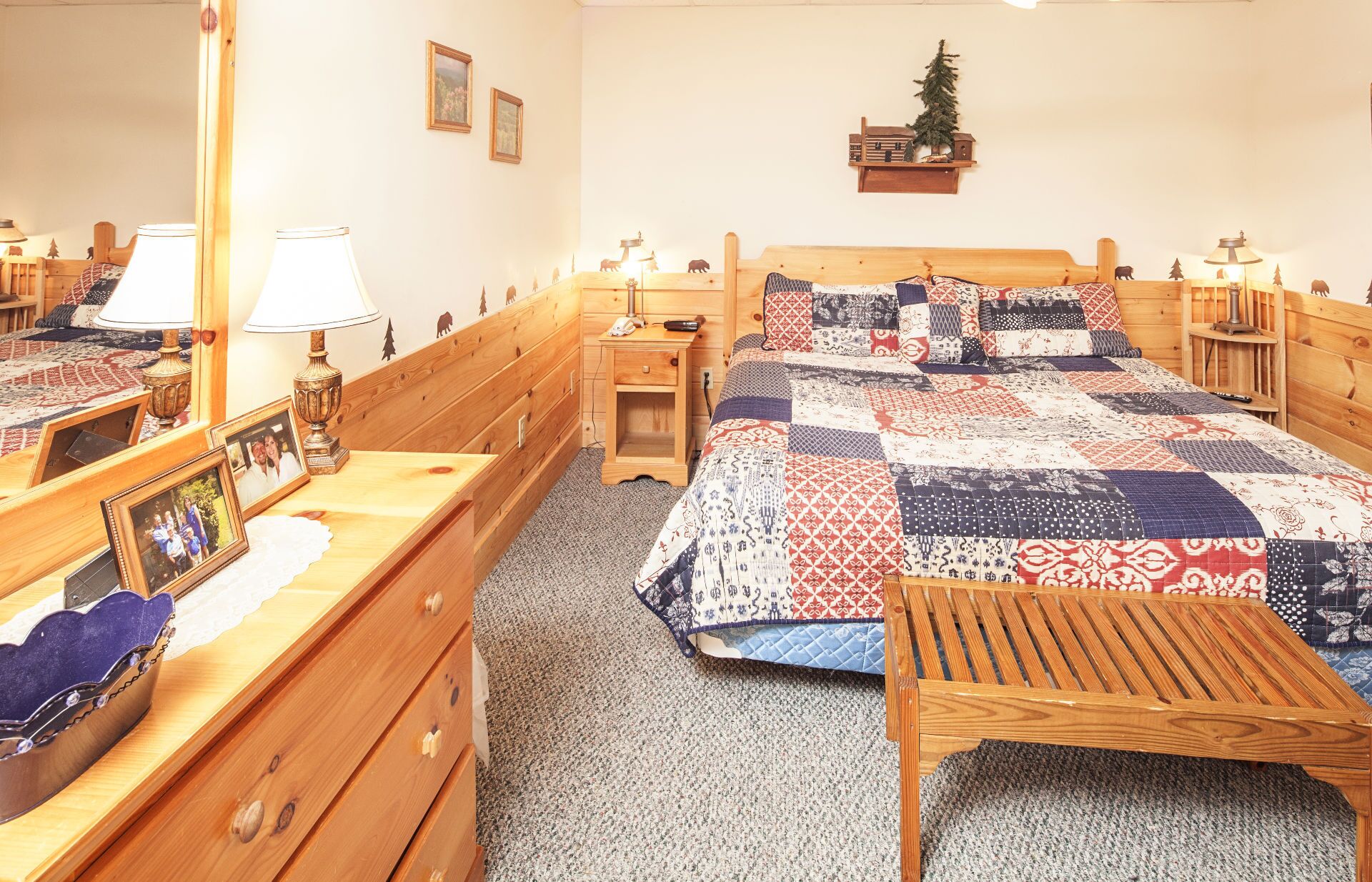 A cozy bedroom with a wooden bed, a nightstand, a dresser, and a mirror.