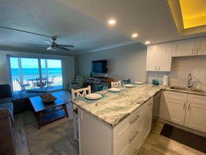 A modern kitchen with a large island, white cabinetry, and a view of the ocean.