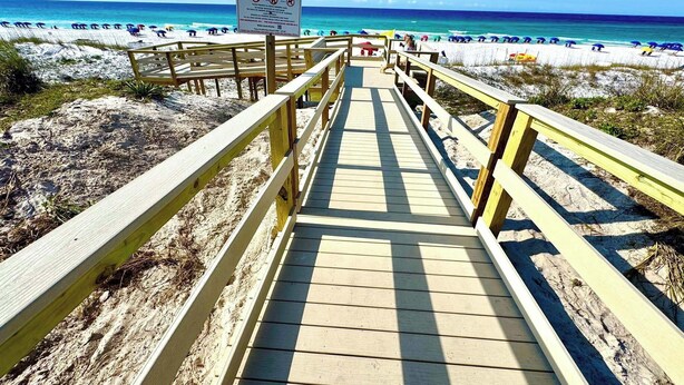 Un muelle de madera que lleva a una playa, con un letrero que indica acceso privado.