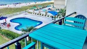 Zona de piscina con vista a la playa, incluyendo sillas de descanso y sombrillas.