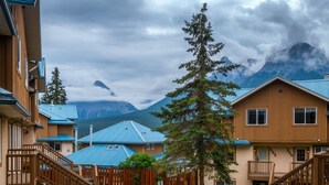 A residential building with a wooden exterior, blue roofs, and a staircase leading to a balcony. - Gorgeous view 2 Storey Townhouse 2 BR/1.5 Bath, A/C, Hot Tub, Fire Pit  (Harvie Heights)
