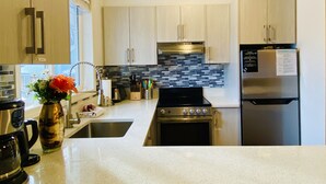 A modern kitchen with light wood cabinets, a stainless steel refrigerator, a built-in oven, and a tiled backsplash. - Gorgeous view 2 Storey Townhouse 2 BR/1.5 Bath, A/C, Hot Tub, Fire Pit  (Harvie Heights)