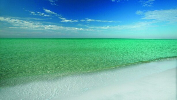 A beach with clear turquoise water and a white sandy shore under a blue sky. - Emerald Coast Vibes & Sunset Views – Islander 517 (Destin)