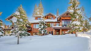 A large, multi-story lodge with a wooden exterior and snow-covered trees in the foreground. - Gondola Ski-in/Ski-out By Tahoe Getaways - Luxury 4 BR, Private Hot Tub, Access to Pool (Truckee)