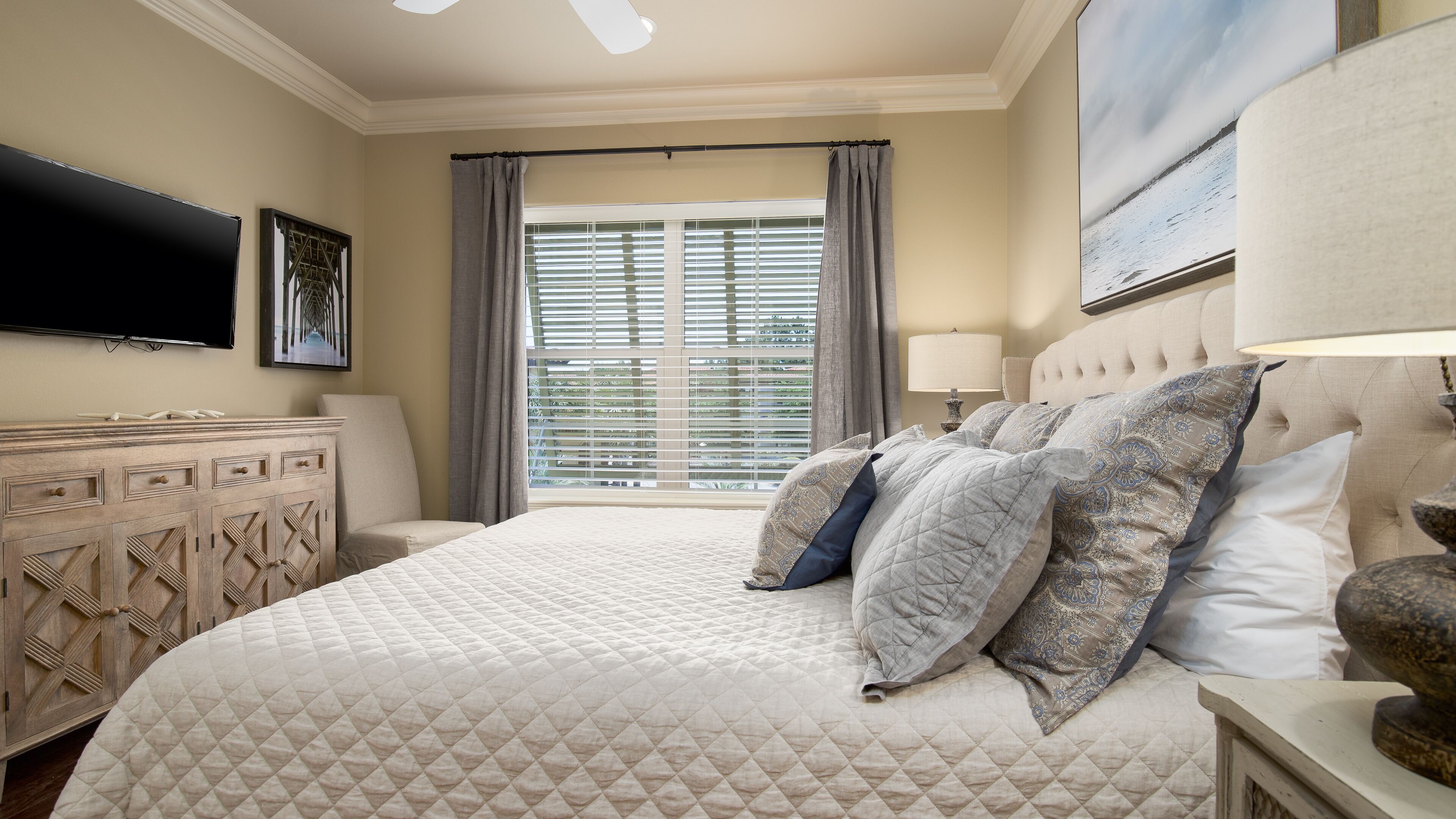 Een hotelkamer met een groot bed, een flatscreen televisie, een dressoir en een raam met zonwering.