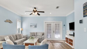 A living room with a ceiling fan, two sofas, a coffee table, and a television.